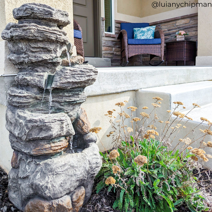 the water fountain is shown in a garden at the edge of the house