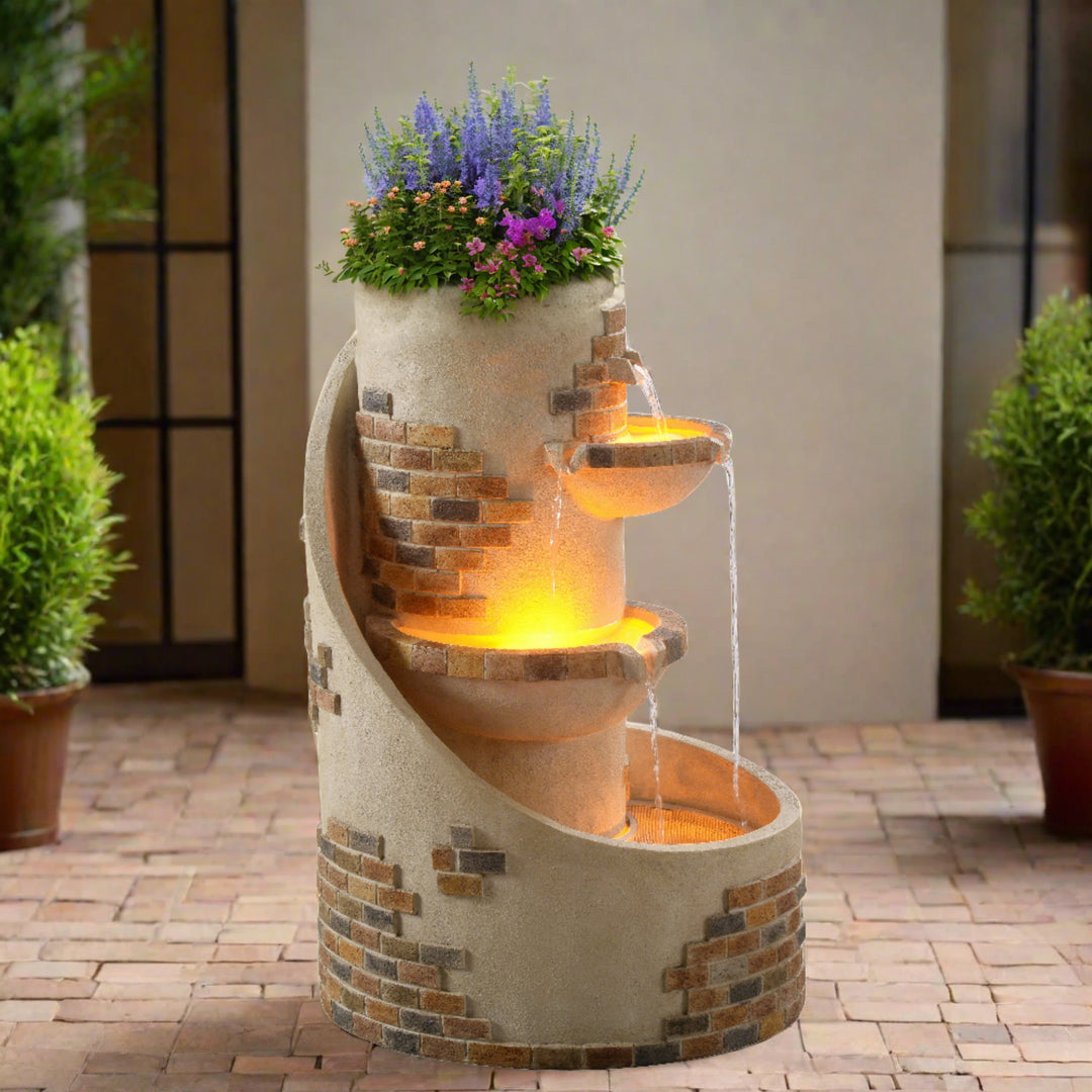 the fountain is displaying wild flowers and flowing water, plus LED lights in a brick patio