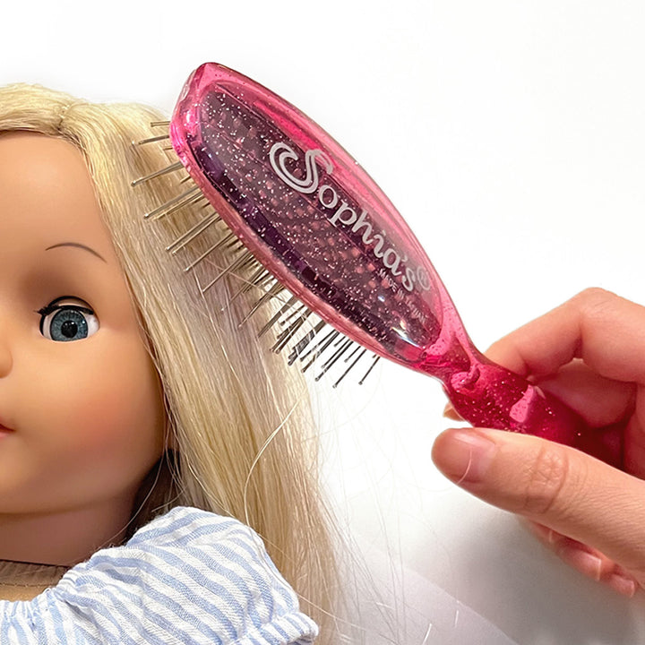 A close up of a girl brushing her blonde Sophia's doll's hair.