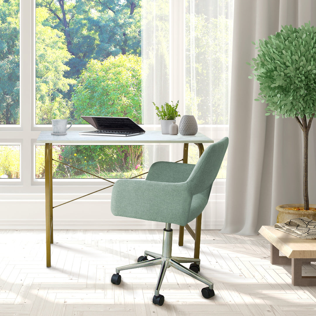 A Teamson Home 40" Home Office Computer Desk with Metal Base, Faux Marble/Brass and chair in a room with a window.